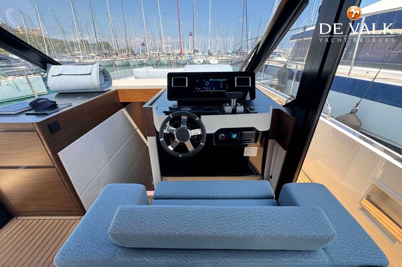 De foto toont het stuur en het dashboard van een boot, met een jachthaven vol zeilboten op de achtergrond. — Wia 520 HT