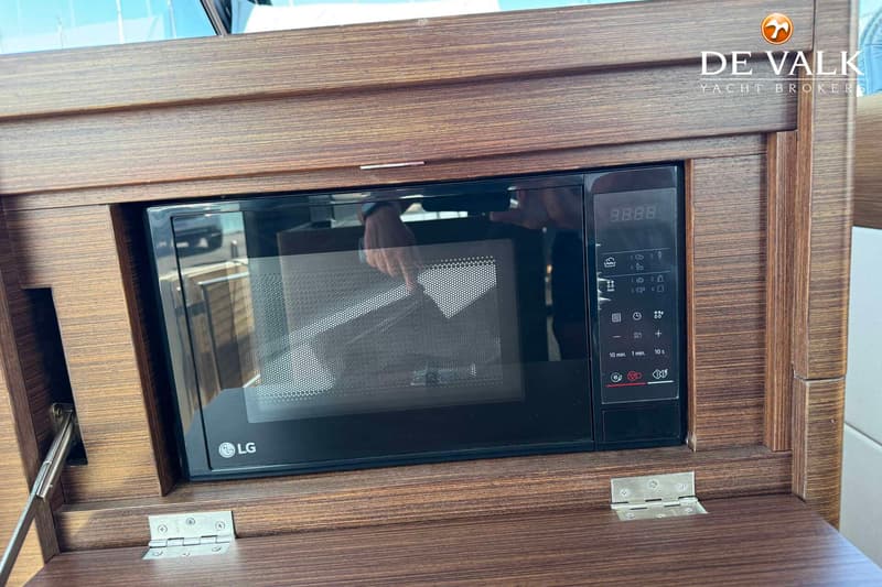 Een ingebouwde zwarte LG magnetron met digitaal display en bedieningspaneel, omringd door donkerbruin hout.