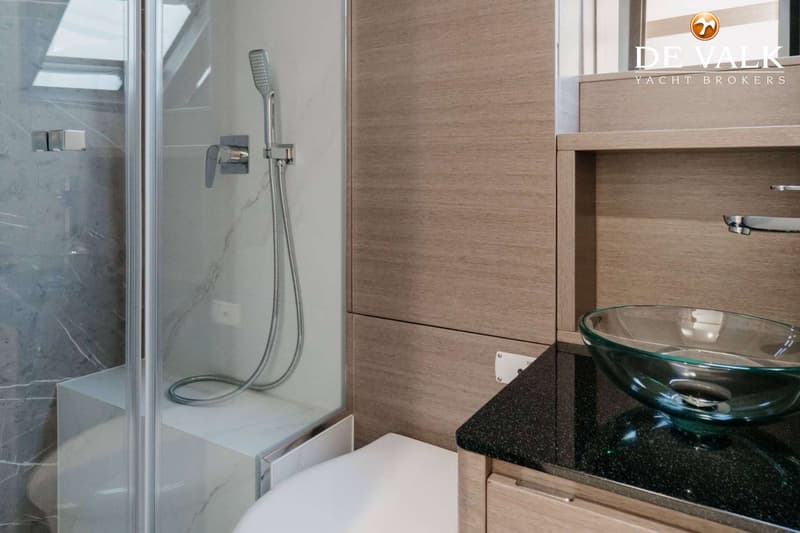 Een badkamer met een douchecabine, een toilet en een wastafel met een glazen kom.