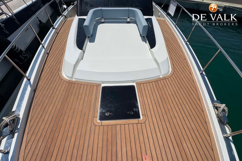 Een bovenaanzicht van het teakhouten dek van een boot met een wit zonnedek en een zwart luik. — Wia 520 HT