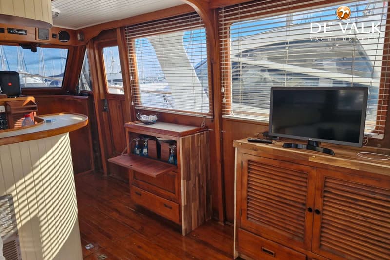 Een interieur van een boot met houten lambrisering, een bar, een tv en ramen met jaloezieën. — CHB Blue Ocean Europa 49