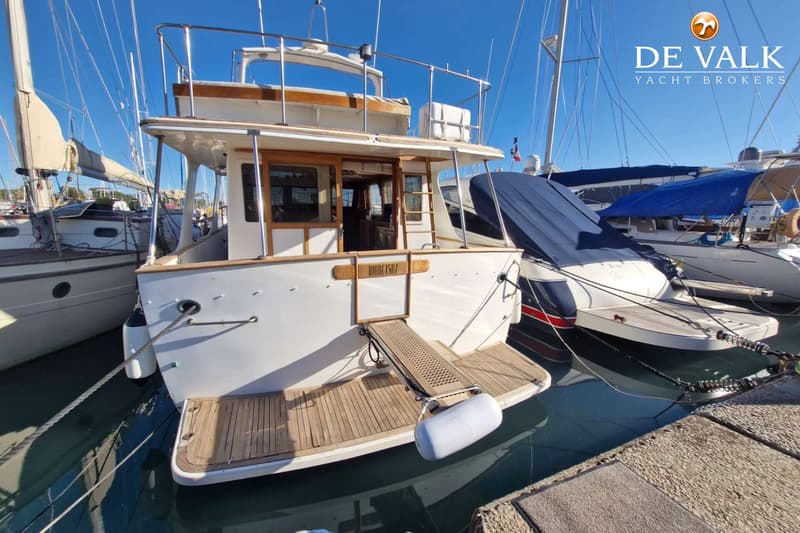 Een witte motorboot met houten details en een zwemplateau ligt aangemeerd in een haven. — CHB Blue Ocean Europa 49
