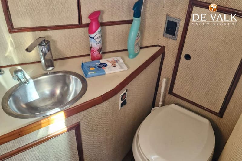 Een badkamer in een boot met een wastafel, toilet, spiegel en schoonmaakmiddelen. — CHB Blue Ocean Europa 49