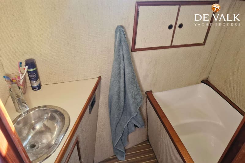 Een badkamer met een wastafel, een handdoek, een bad en een kastje.