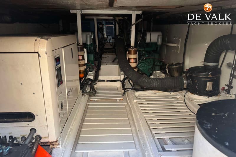 Een machinekamer met twee motoren, een generator en een houten vloer.