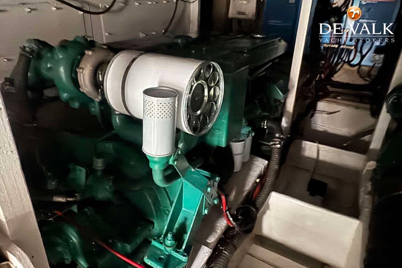 Een close-up van een groene scheepsmotor met een wit luchtfilter en diverse leidingen.