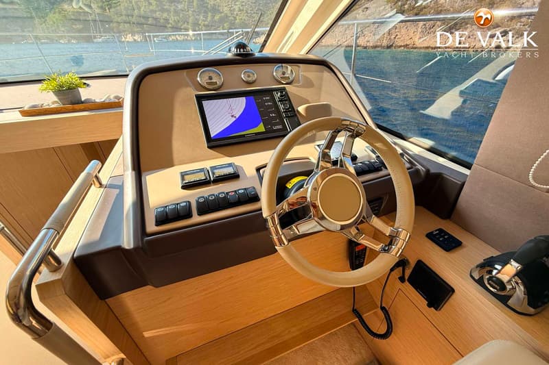 Een stuurstand van een boot met een beige stuurwiel, een Garmin-scherm, diverse meters en schakelaars.