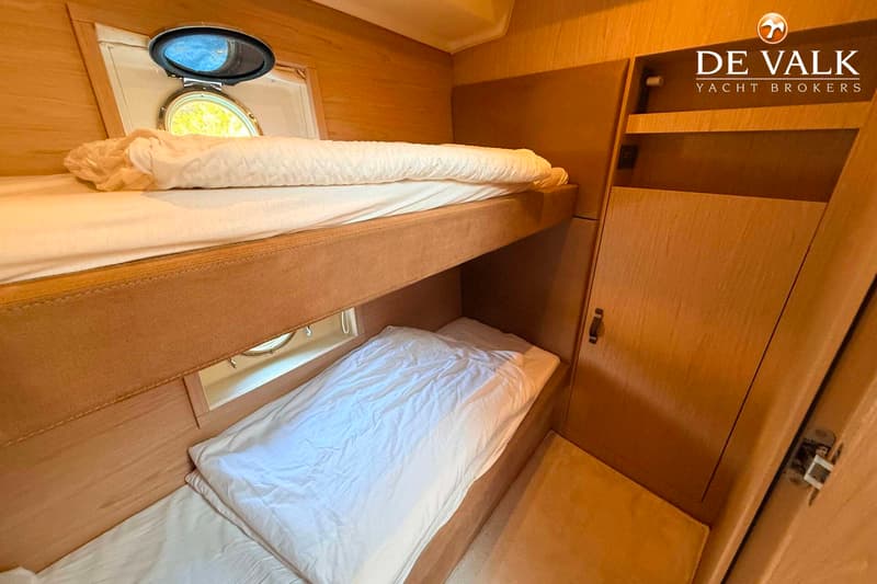 Een kajuit met twee stapelbedden, een patrijspoort en een kast. — Beneteau Monte Carlo 5