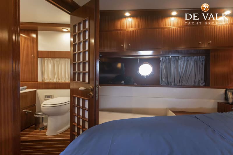 Een interieur van een boot met een open deur naar een toiletruimte en een bed met blauw beddengoed. — Navalia Romantica 65