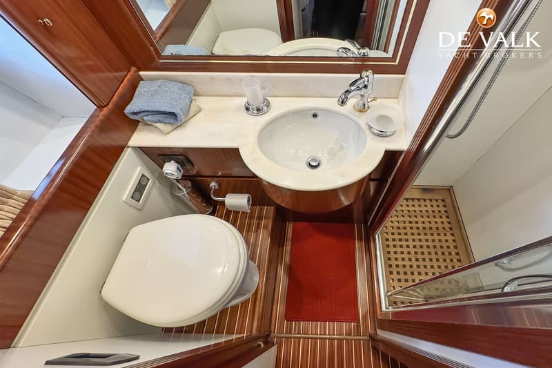 Een badkamer met een toilet, wastafel, spiegel en een douchecabine met houten vloerrooster.