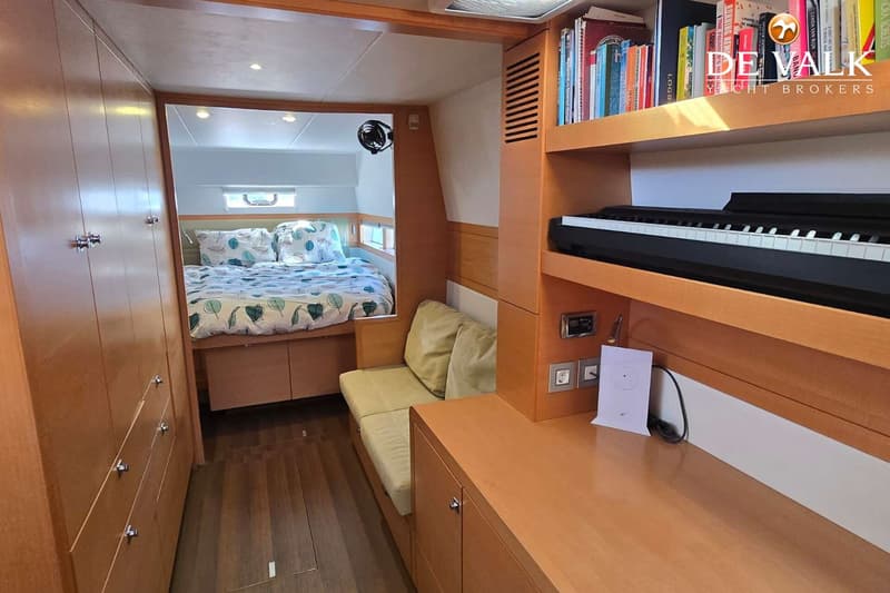 De foto toont een interieur met een bed, een bankje, een bureau met een keyboard en boekenplanken.