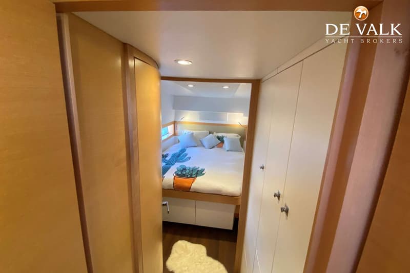 Een doorkijk naar een slaapkamer met een tweepersoonsbed, witte kussens en een dekbed met cactusprint.