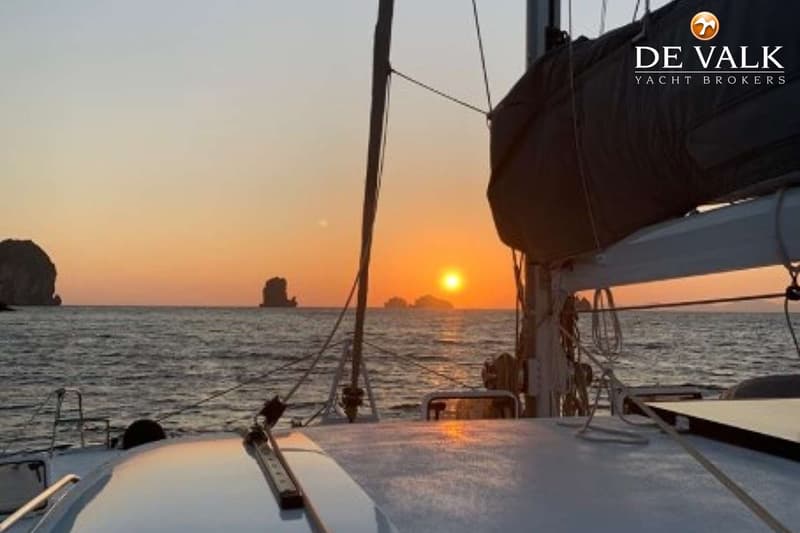 Een zeilboot op zee bij zonsondergang met rotsformaties op de achtergrond. — Punch 1500 LC