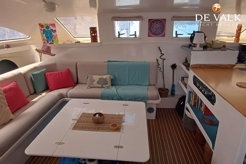 Een interieur van een boot met een witte bank, kussens, een tafel en ramen met uitzicht op water. — Punch 1500 LC