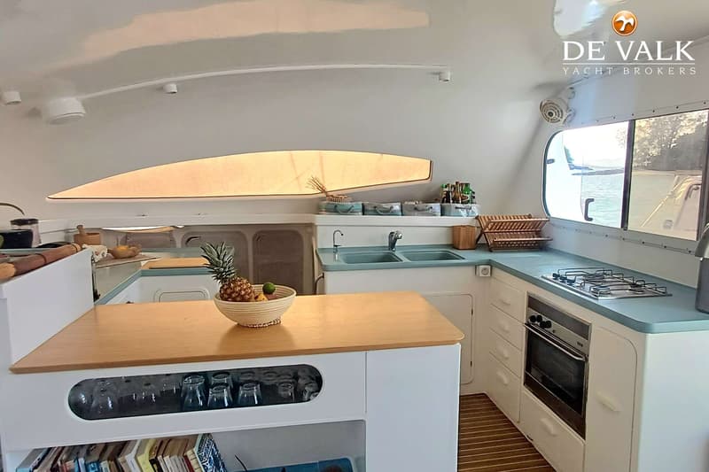 Een kombuis met een houten aanrechtblad, een wasbak, een gasfornuis, een oven en een raam met uitzicht op water.