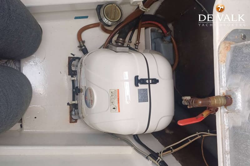 Een witte boiler met slangen en kabels is gemonteerd in een boot, met twee grijze stootwillen links in beeld. — Punch 1500 LC