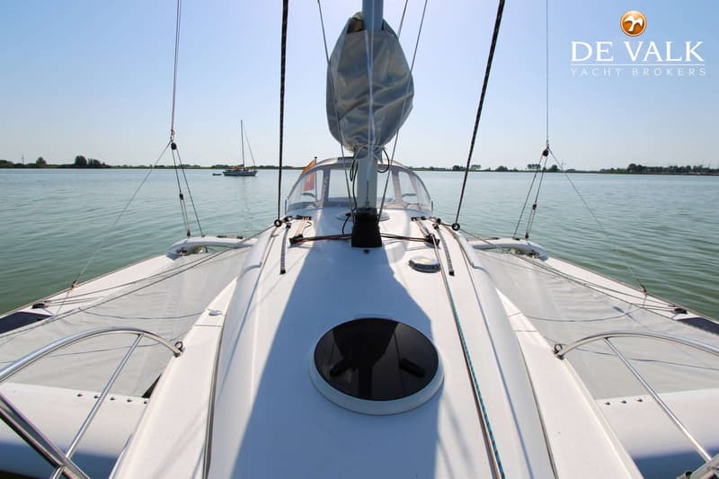 Een witte zeilboot met een opgerold zeil en een rond luik op het dek, varend op rustig water. — Dragonfly DF 28 Touring