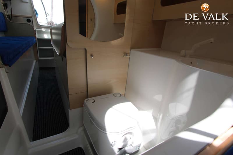 De foto toont een interieur van een boot met een toilet, wastafel en een doorgang naar een slaapgedeelte.