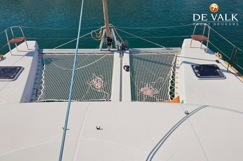 Een bovenaanzicht van het voordek van een catamaran met twee witte netten en twee stoelen.