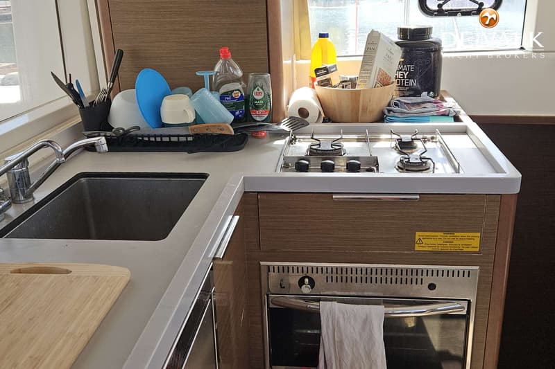 De foto toont een kombuis met een gootsteen, een fornuis met twee pitten en een oven, en diverse keukenbenodigdheden.