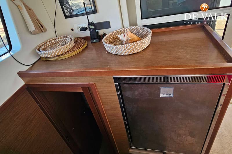 Een houten aanrecht met een ingebouwde Isotherm koelkast, twee mandjes en een portofoon.