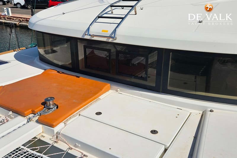 Een deel van een witte boot met oranje kussens, een ankerlier, ramen en een ladder op het dak is zichtbaar. — Lagoon 40