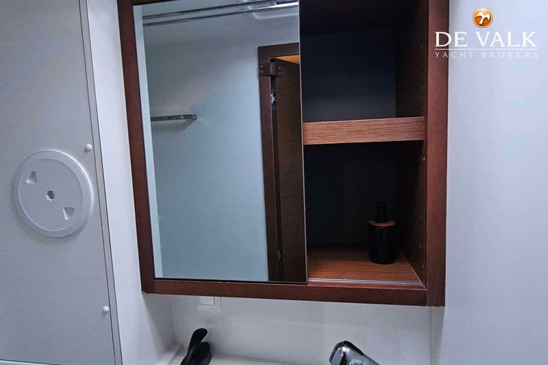 Een badkamerkastje met een spiegeldeur en een open vak met een flesje erin.