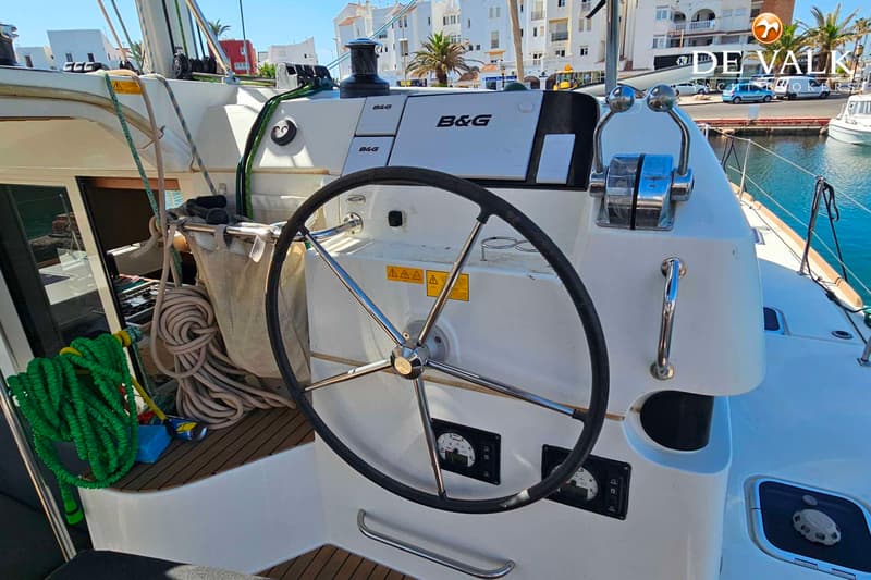 Een stuurwiel, gashendel en navigatie-instrumenten van B&G zijn zichtbaar op een boot in een haven. — Lagoon 40