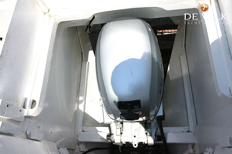 Een zilverkleurige buitenboordmotor is gemonteerd in een witte motorbun.