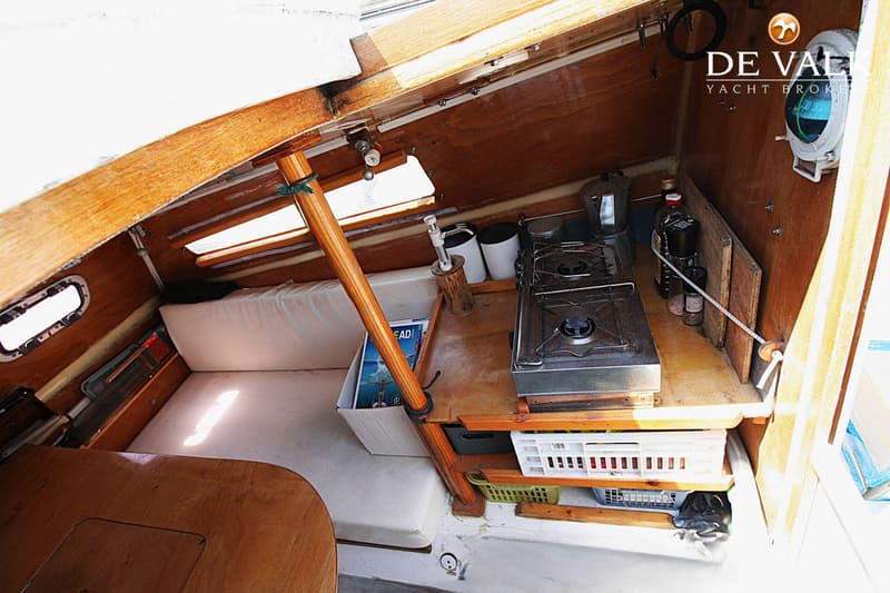 De foto toont het interieur van een boot met een kooktoestel, een tafel en een slaapplaats. — Wharram Tiki 30