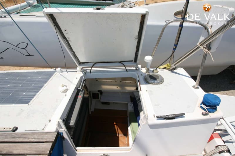 Een open luik van een boot met een zonnepaneel en een blauwe hoes over een lier. — Wharram Tiki 30