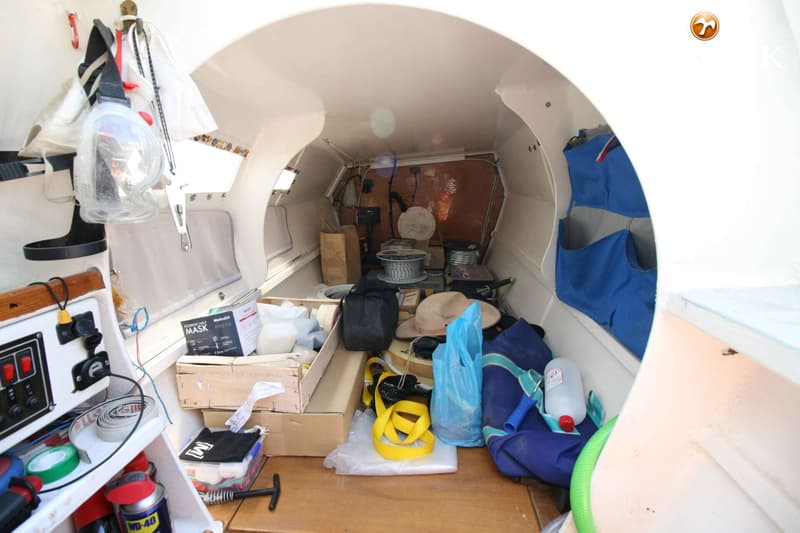 De foto toont het interieur van een bootkajuit, gevuld met diverse spullen en gereedschappen.