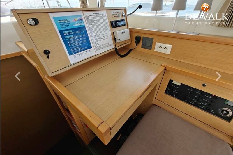 Een houten navigatiestation met een opklapbaar paneel met documenten, een radio, een B&G-apparaat, een microfoon en…