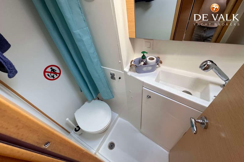 Een badkamer met een toilet, een wastafel met kraan, een spiegel en een blauw douchegordijn.