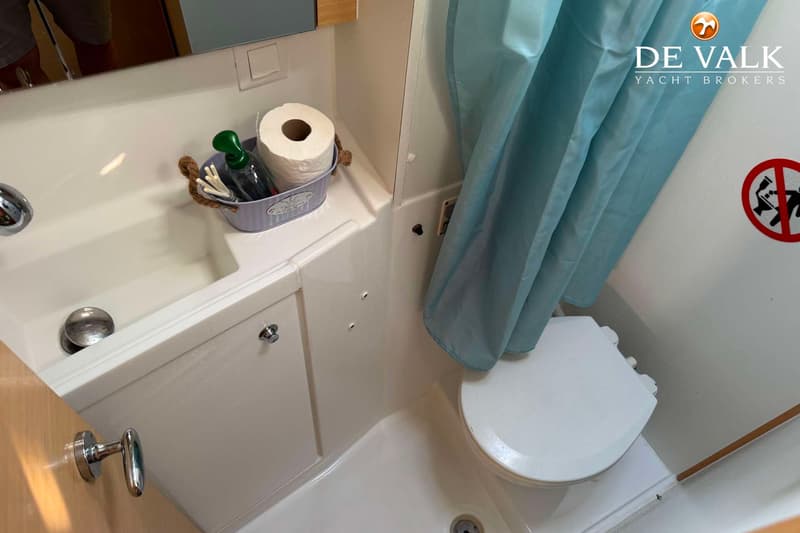 Een badkamer met een wastafel, toilet, douchegordijn en een opbergmandje met toiletpapier en zeep.