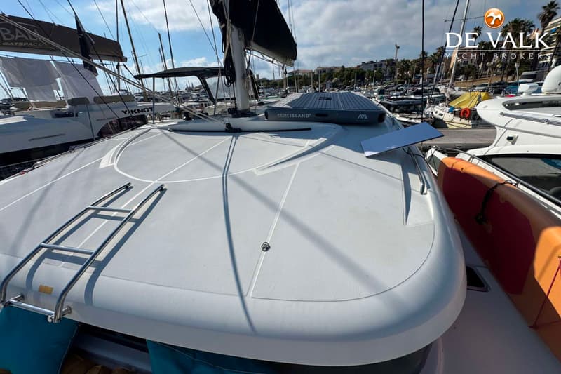 Een wit dek met een zilverkleurige ladder, een opblaasbaar platform en een oranje kajak. — Lagoon 39