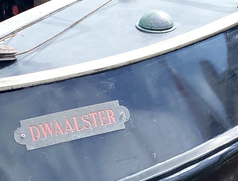 Een deel van een donkerblauwe boot met een naamplaatje waarop "DWAALSTER" staat. — Schokker 14.00 M. One Off
