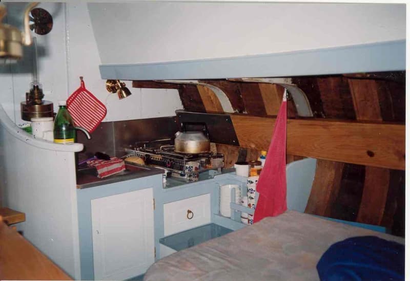 Een interieur van een boot met een kombuis, een bed en houten spanten. — Boeier Lantinga 900
