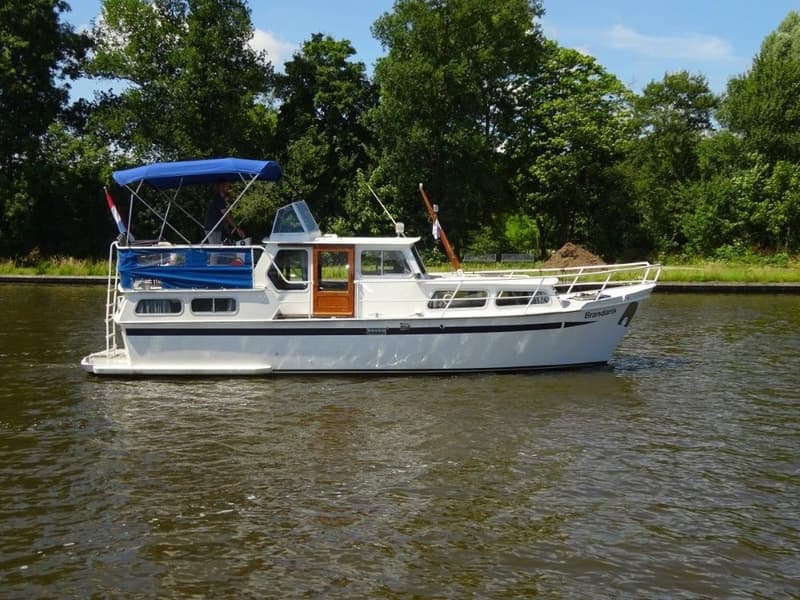 Een witte motorboot met blauwe kap en de naam "Brandaris" op de boeg vaart op het water. — Pedro Kruiser 1000 AK
