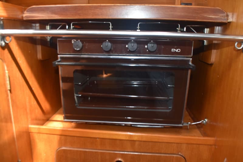 Een ingebouwde ENO-oven met vier zwarte draaiknoppen en een glazen deur, omringd door houten panelen.