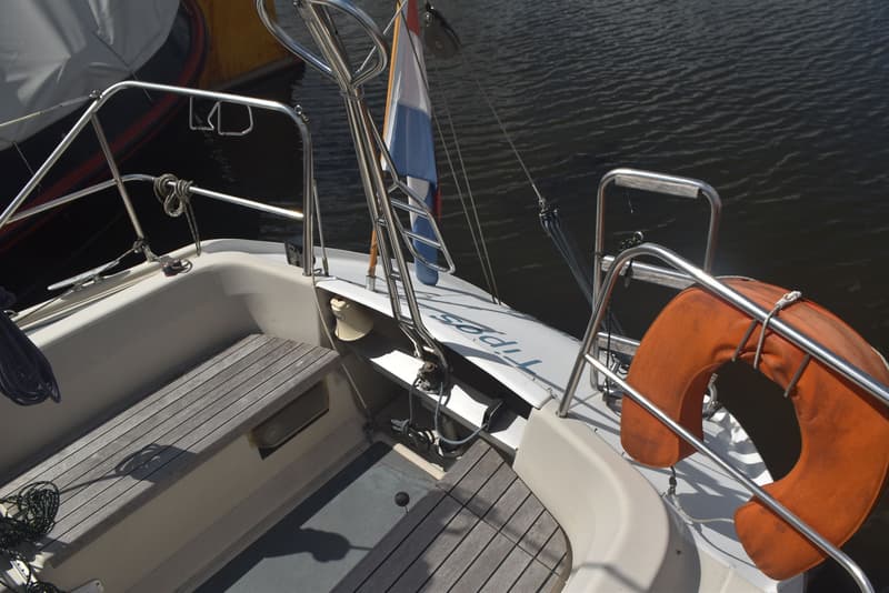 De foto toont de achtersteven van een boot met een reddingsboei, een Nederlandse vlag, en de naam "Tipos" op de spiegel.