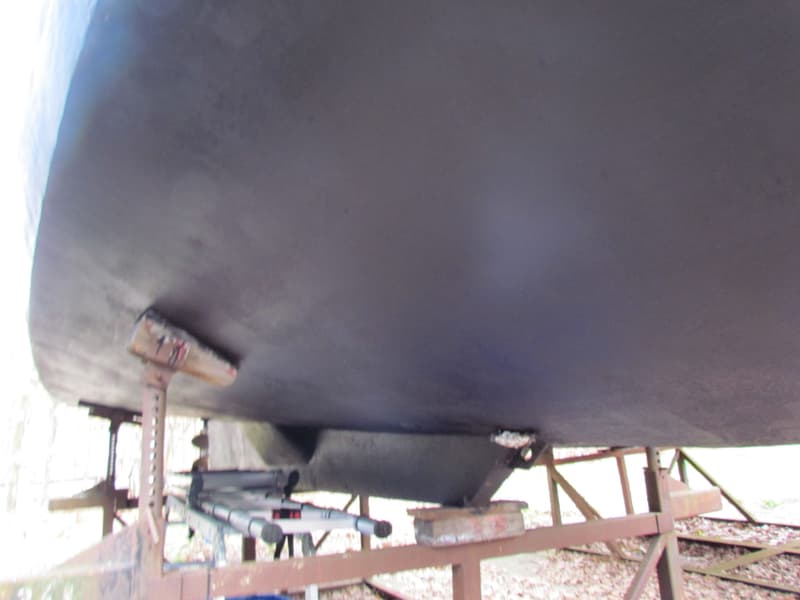 De onderkant van een donkere boot, ondersteund door metalen bokken, met een kiel en roer zichtbaar. — Curtevenne 950 GSAK