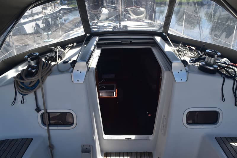 Een open kajuitingang van een zeilboot met een transparante buiskap, lieren en touwen op het dek. — Beneteau Oceanis 37
