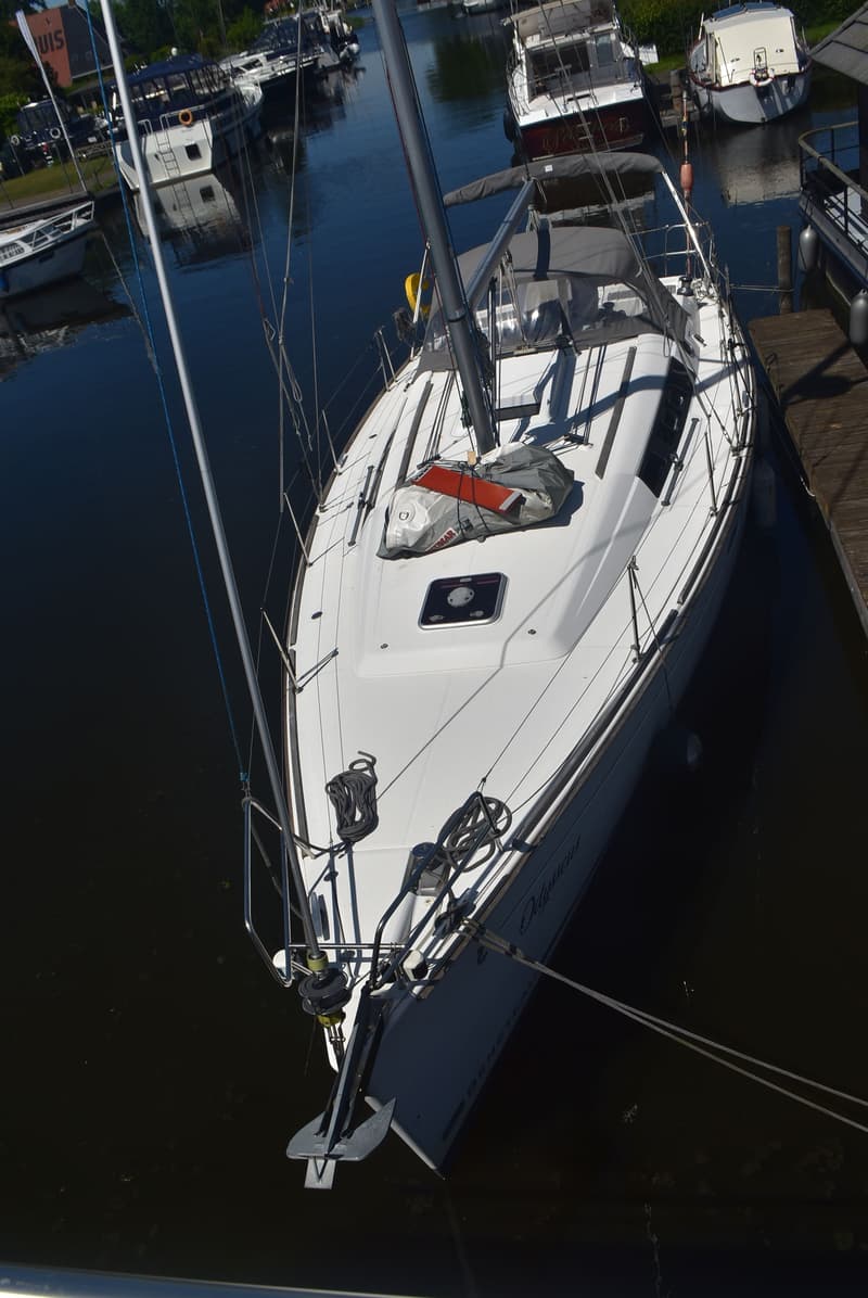 Een witte zeilboot met de naam "Odysseus" ligt aangemeerd aan een houten steiger. — Beneteau Oceanis 37