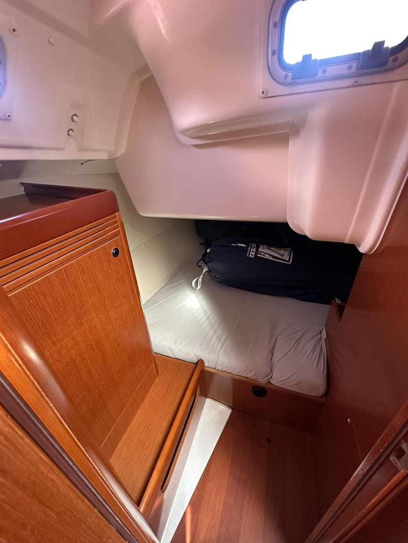 Een kajuit met een bed, houten panelen en een patrijspoort. — Beneteau Oceanis 37