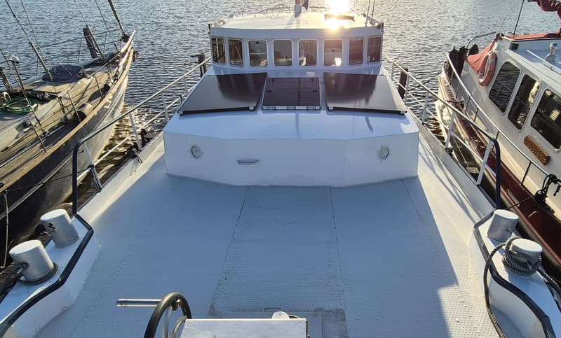Een wit schip met een stuurhut en twee zonnepanelen op het voordek, geflankeerd door twee andere boten. — Botter 14.99
