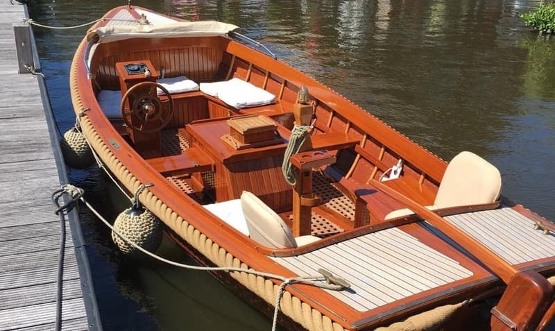 Een houten boot met een touw langs de rand, liggend aan een houten steiger. — De Jongvlet 6.20