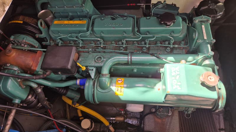 Een close-up van een groene Volvo Penta scheepsmotor met diverse slangen, leidingen en waarschuwingsstickers.