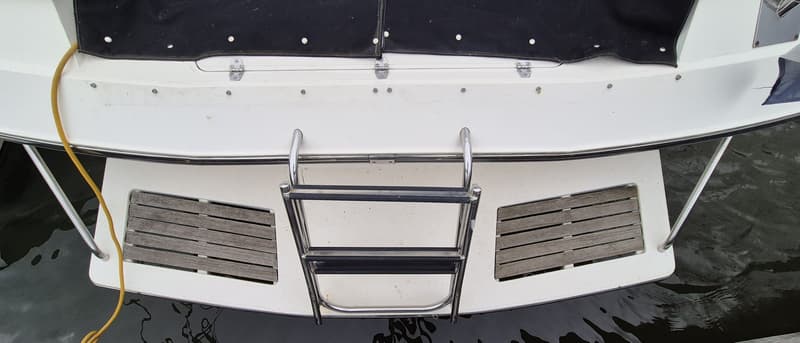 Een detailfoto van de achterkant van een boot met een zwemplateau, een zwemtrap en een geel touw. — Sunseeker 38 Martinique