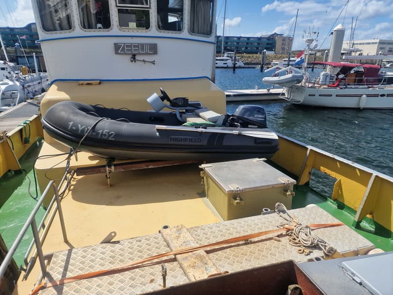 Een grijze rubberboot met een Yamaha buitenboordmotor ligt op het dek van een boot genaamd "ZEEUIL".